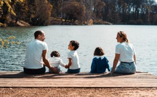 A family of five relaxing by a serene lake in Lyon, France on a sunny day.