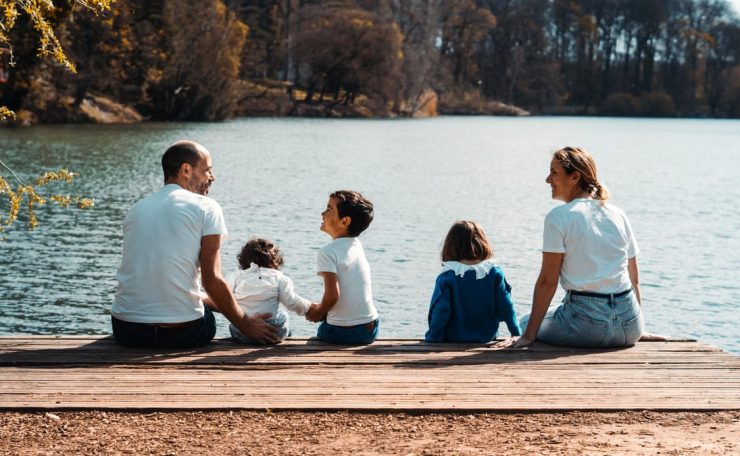 A family of five relaxing by a serene lake in Lyon, France on a sunny day.